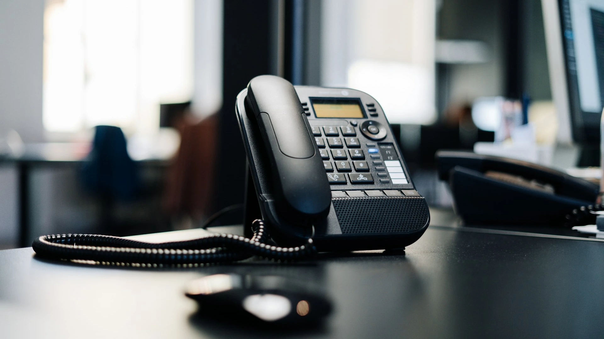 black ip desk phone on black wooden table